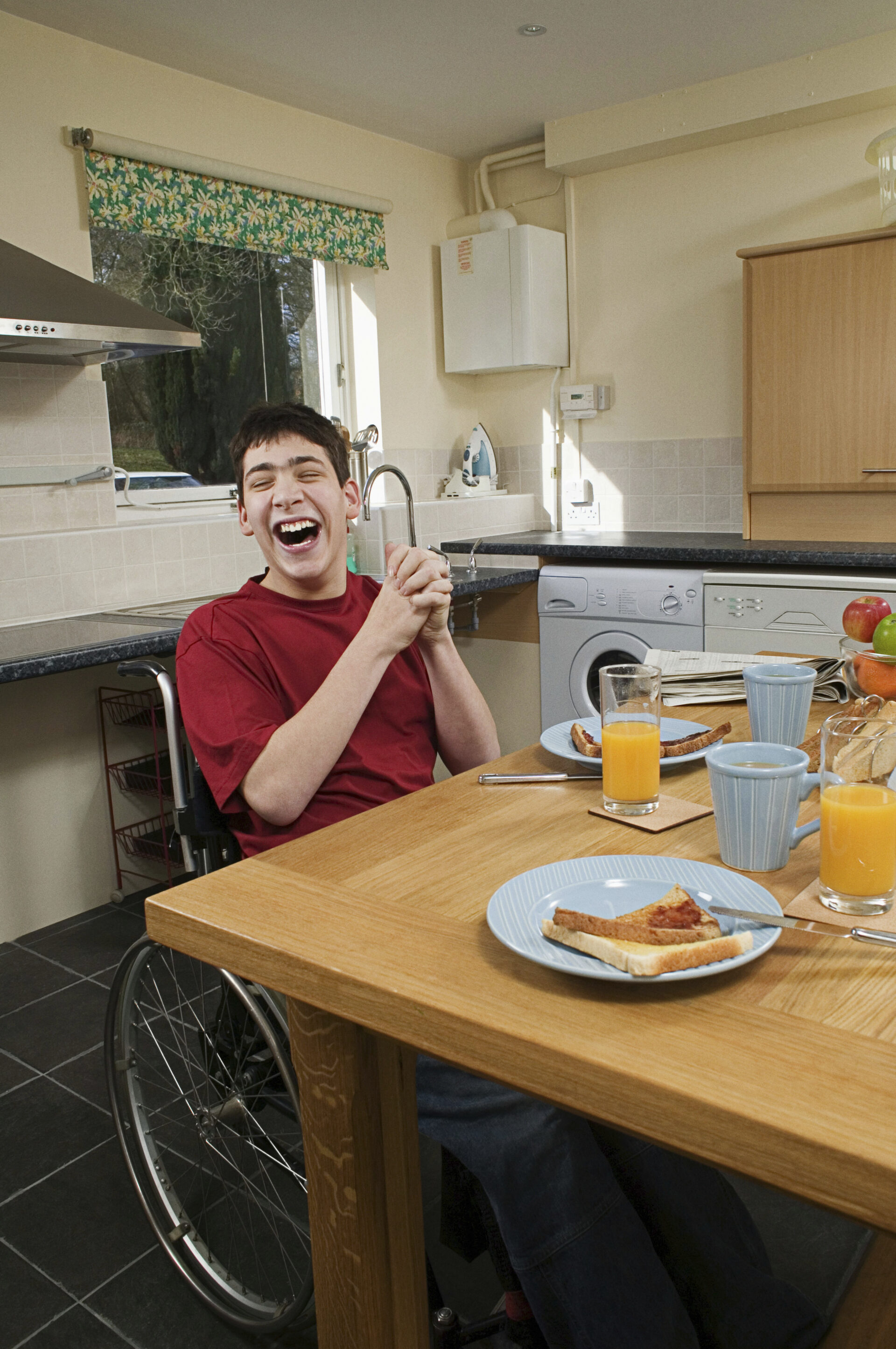 Disabled man laughing at breakfast table at one of our Care Homes in Ashford, Kent
