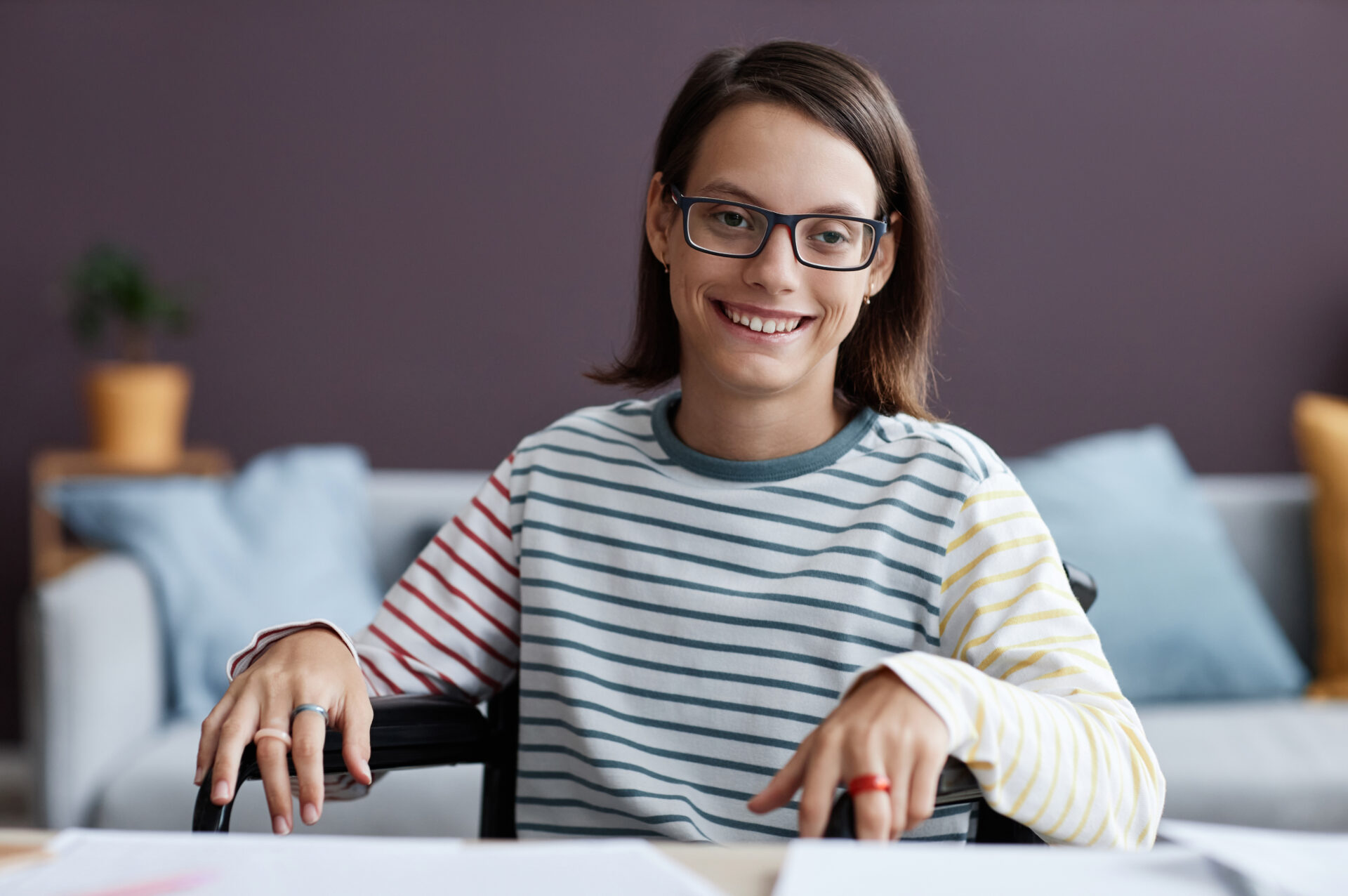Teenage girl with disability wearing glasses and smiling at camera